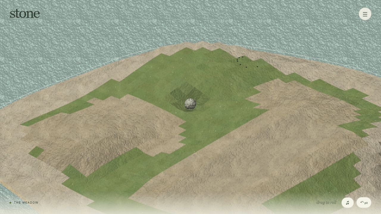 A stone resting on a grassy island surrounded by sand and sea.